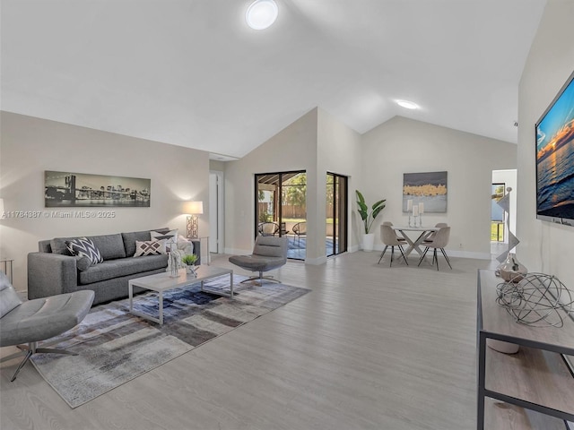 living area featuring high vaulted ceiling, baseboards, and wood finished floors