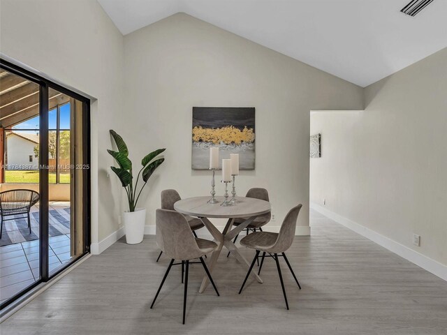 dining room featuring baseboards, vaulted ceiling, wood finished floors, and visible vents