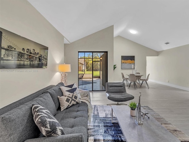 living area featuring baseboards, visible vents, wood finished floors, and high vaulted ceiling