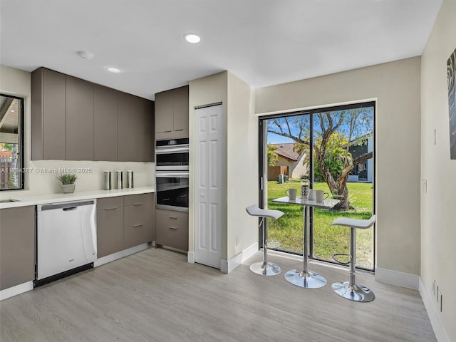 kitchen with light wood-style floors, baseboards, light countertops, gray cabinetry, and stainless steel appliances