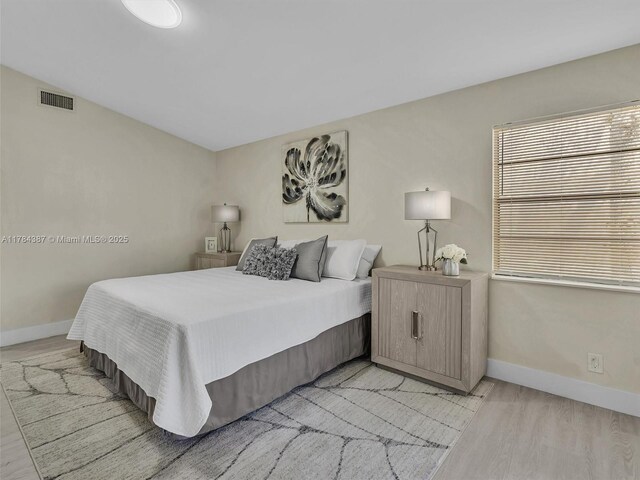 bedroom with visible vents, baseboards, and light wood-type flooring