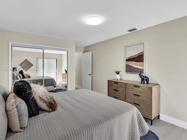 bedroom featuring light wood-style floors, baseboards, a closet, and visible vents