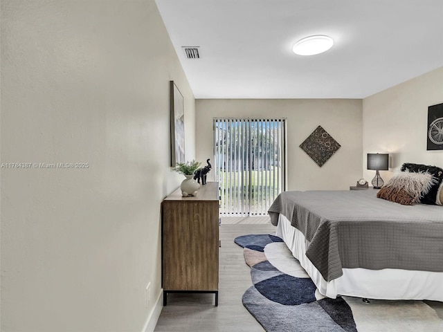 bedroom with access to outside, baseboards, wood finished floors, and visible vents