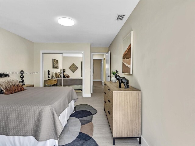 bedroom featuring a closet, baseboards, visible vents, and light wood-type flooring