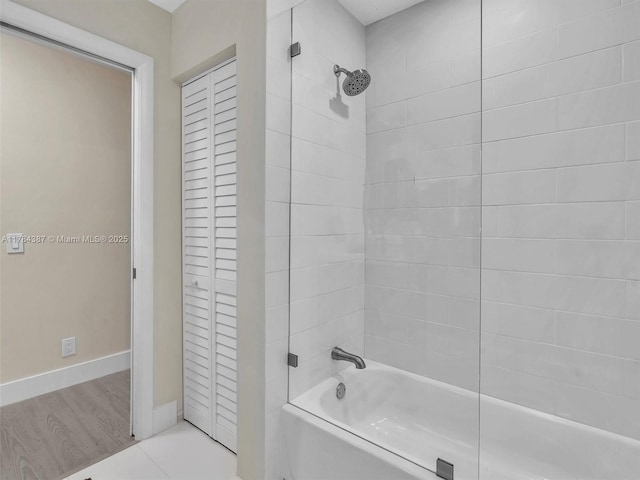 bathroom featuring baseboards, a closet, and tub / shower combination