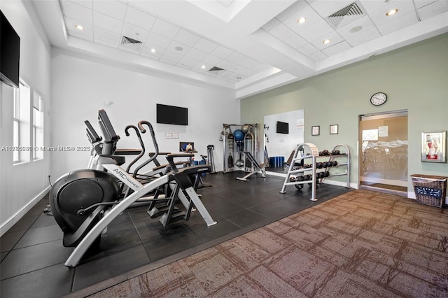 exercise room featuring baseboards, a towering ceiling, and visible vents
