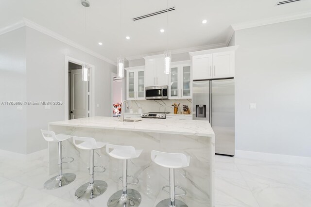 398 35th Ave NW, Naples, FL 34120 - kitchen with marble finish floor, stainless steel appliances, ornamental molding, a sink, and a kitchen island with sink