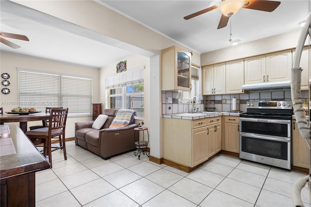 kitchen featuring tile counters, a sink, light tile patterned floors, range with two ovens, and ceiling fan