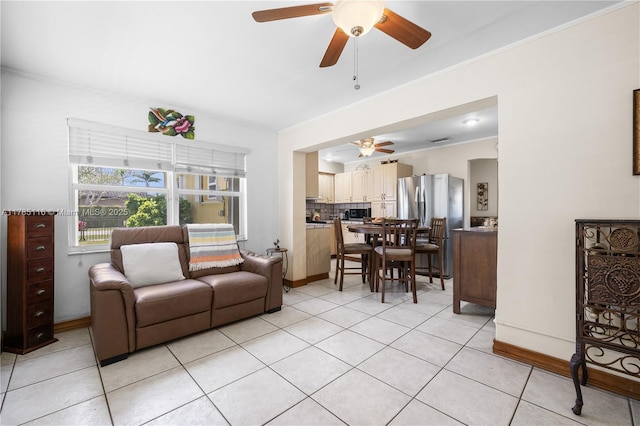 living room featuring light tile patterned floors, baseboards, ceiling fan, and crown molding