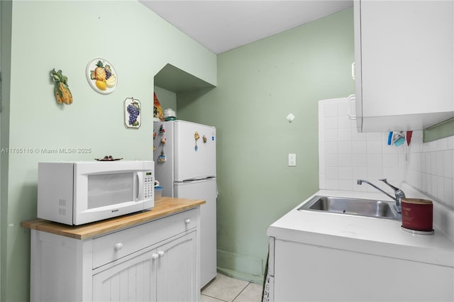 kitchen with tasteful backsplash, a sink, wood counters, light tile patterned flooring, and white appliances