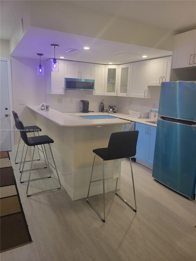 2900 Banyan St Unit 303, Fort Lauderdale, FL 33316 - kitchen with freestanding refrigerator, a kitchen bar, white cabinets, light wood-style floors, and recessed lighting