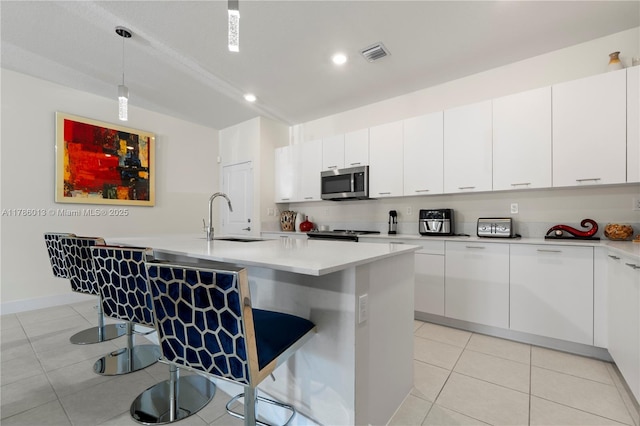 8292 NW 43rd St, Doral, FL 33166 - kitchen with stainless steel microwave, light tile patterned floors, white cabinets, light countertops, and recessed lighting