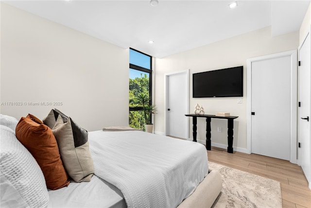 bedroom with floor to ceiling windows, light wood-style flooring, baseboards, and recessed lighting