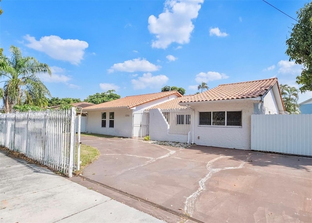 mediterranean / spanish-style home with fence, a tile roof, and stucco siding