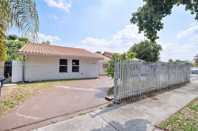 exterior space featuring a gate, a tile roof, stucco siding, and fence