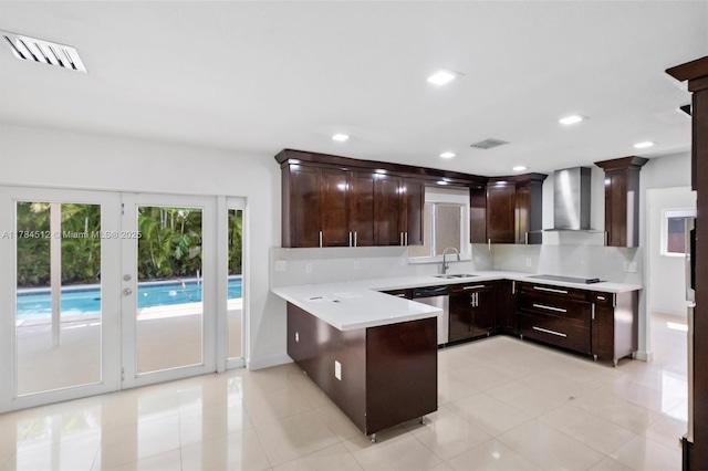 kitchen with wall chimney exhaust hood, a peninsula, stainless steel dishwasher, a sink, and black electric stovetop