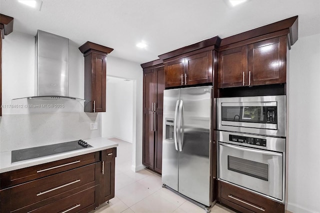 kitchen with wall chimney exhaust hood, dark brown cabinets, appliances with stainless steel finishes, light countertops, and light tile patterned floors