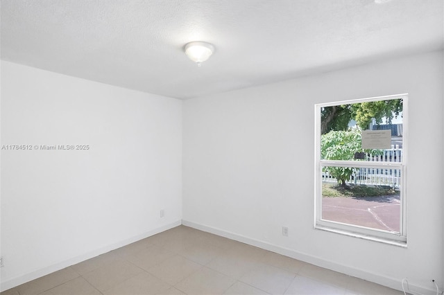 spare room featuring baseboards and a textured ceiling