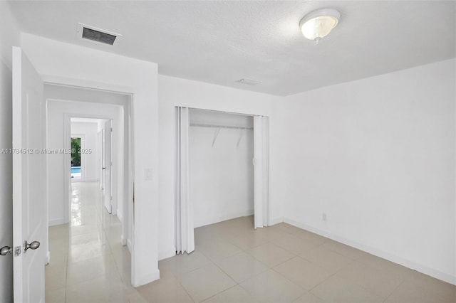 unfurnished bedroom with baseboards, visible vents, and a closet