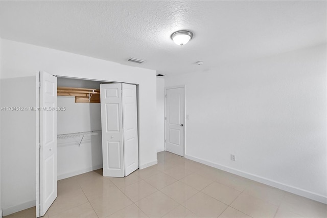 unfurnished bedroom with baseboards, visible vents, a textured ceiling, and a closet