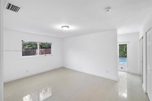 empty room featuring plenty of natural light, baseboards, visible vents, and light tile patterned floors