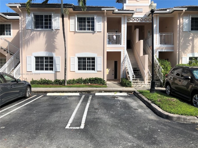 view of building exterior with stairs and uncovered parking