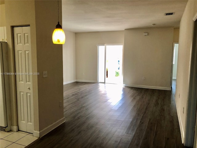 spare room with baseboards, wood finished floors, and visible vents