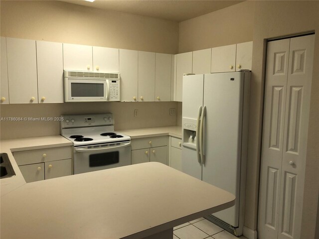 kitchen with a peninsula, light countertops, white appliances, and light tile patterned floors