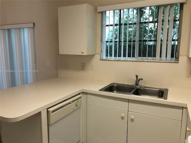 kitchen featuring white cabinets, light countertops, a sink, white dishwasher, and a peninsula