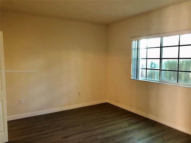 empty room with dark wood finished floors and baseboards