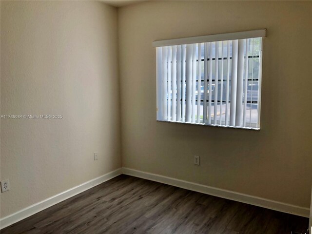 unfurnished room with baseboards and dark wood-style flooring
