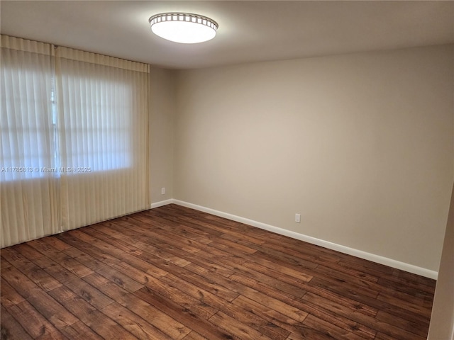 unfurnished room with baseboards and dark wood-style flooring