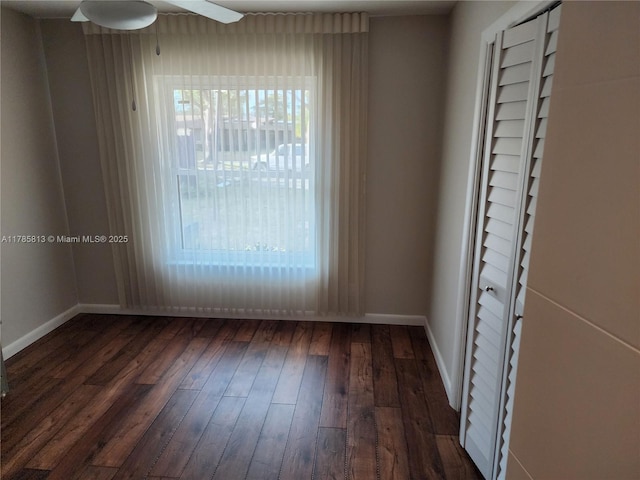empty room with baseboards, dark wood-style floors, and ceiling fan