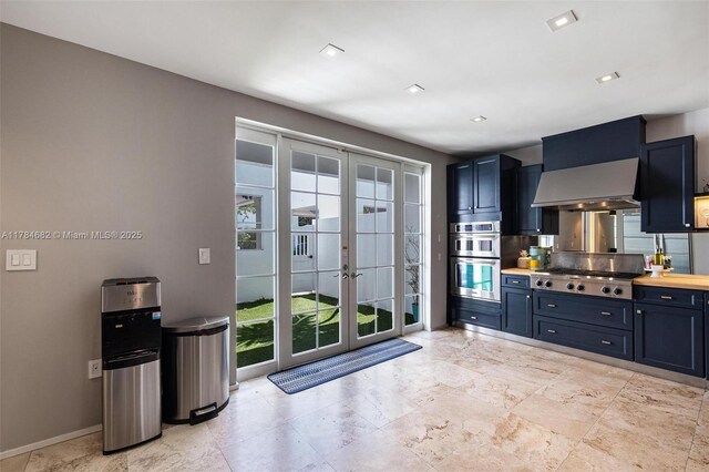 7765 SW 54th Ct Unit 7765, Miami, FL 33143 - kitchen featuring baseboards, french doors, light countertops, wall chimney exhaust hood, and appliances with stainless steel finishes