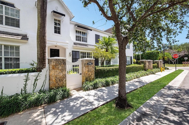 7765 SW 54th Ct Unit 7765, Miami, FL 33143 - view of front facade featuring stucco siding, a gate, stone siding, and a fenced front yard