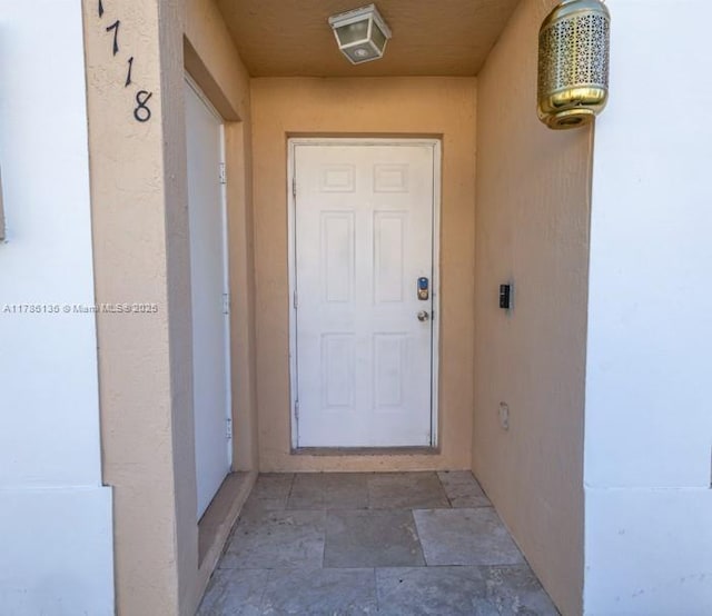 doorway to property with stucco siding and visible vents