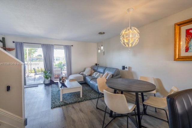 dining area with baseboards, wood finished floors, and an inviting chandelier