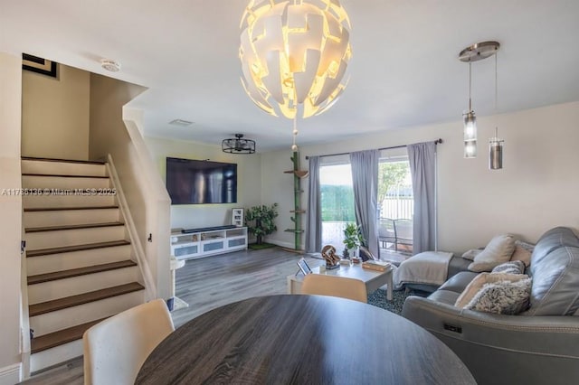 living room with a notable chandelier, baseboards, wood finished floors, and stairs