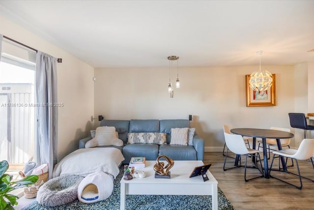 living area with baseboards, wood finished floors, and a notable chandelier