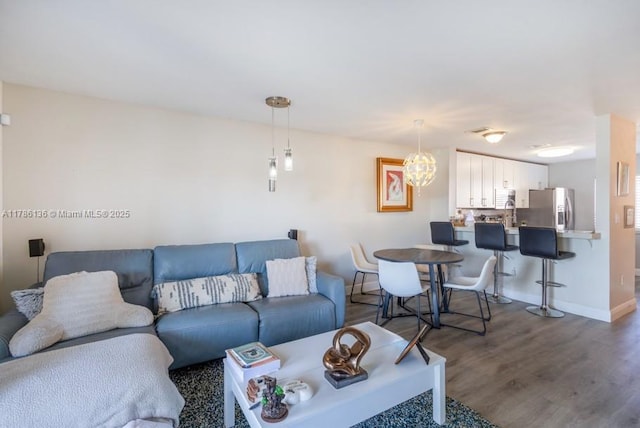 living area featuring dark wood finished floors, baseboards, and a chandelier