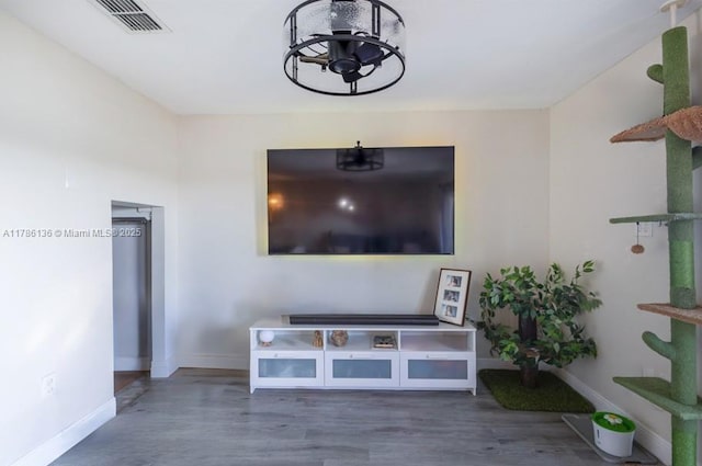 living room featuring wood finished floors, visible vents, baseboards, and a notable chandelier