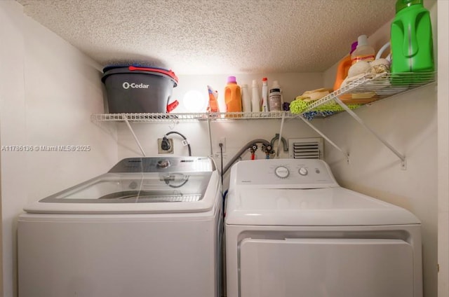 clothes washing area featuring laundry area, washer and clothes dryer, and a textured ceiling