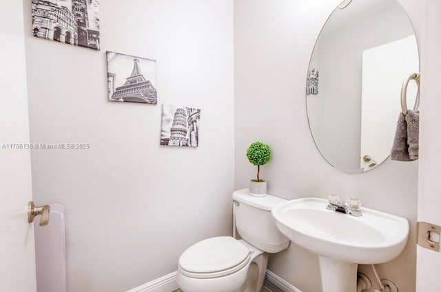 bathroom with baseboards, a sink, and toilet