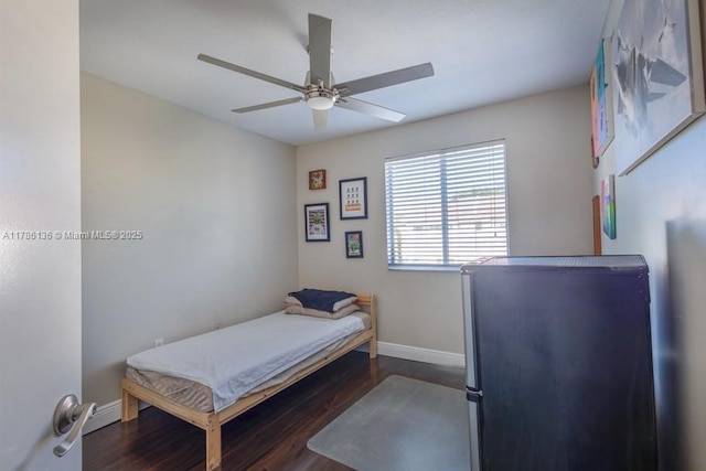 bedroom featuring ceiling fan, baseboards, wood finished floors, and freestanding refrigerator