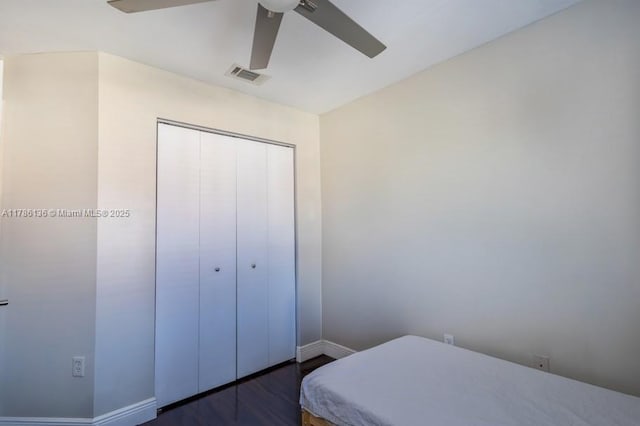 bedroom featuring dark wood-style floors, baseboards, visible vents, a ceiling fan, and a closet