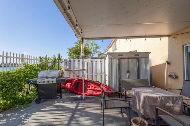 view of patio featuring grilling area, fence, an outbuilding, and a storage unit
