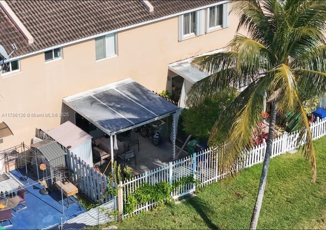 rear view of house with stucco siding and a fenced backyard
