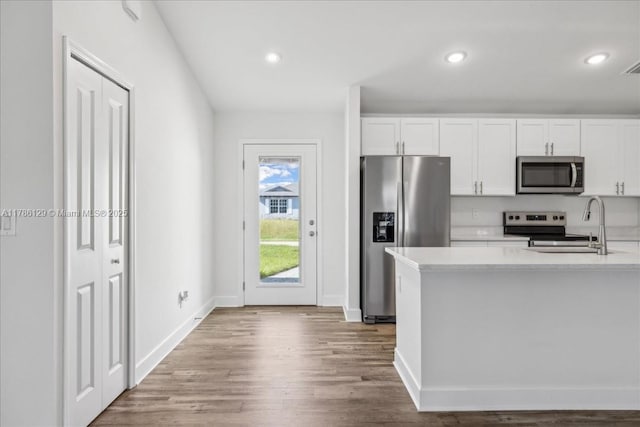 1909 NE 2nd Ave, Cape Coral, FL 33909 - kitchen with appliances with stainless steel finishes, white cabinetry, light countertops, wood finished floors, and recessed lighting