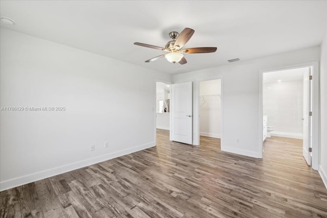 1909 NE 2nd Ave, Cape Coral, FL 33909 - unfurnished bedroom with wood finished floors, a closet, a walk in closet, baseboards, and ensuite bathroom
