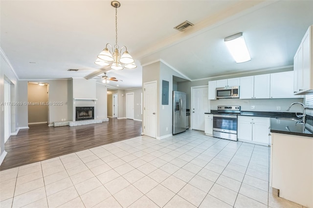kitchen featuring crown molding, a sink, stainless steel appliances, lofted ceiling, and visible vents